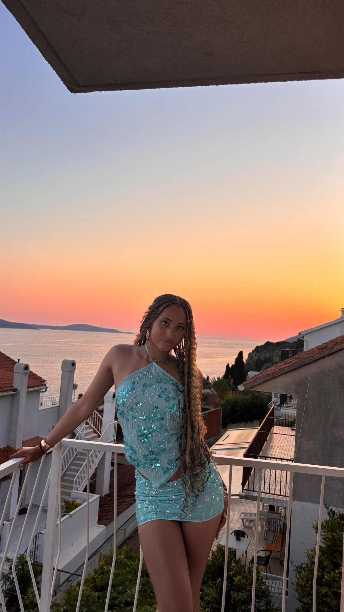 Lytoya Ri standing on a balcony beside the sea at sunset