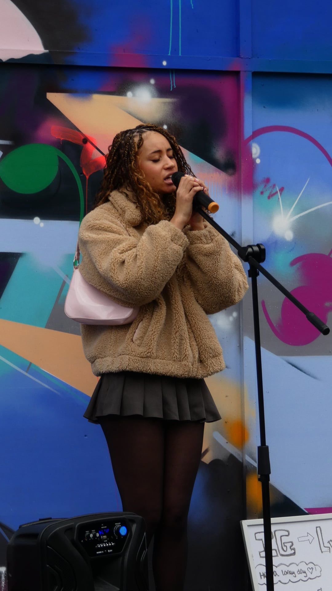 Lytoya Ri singing in front of a colourful mural