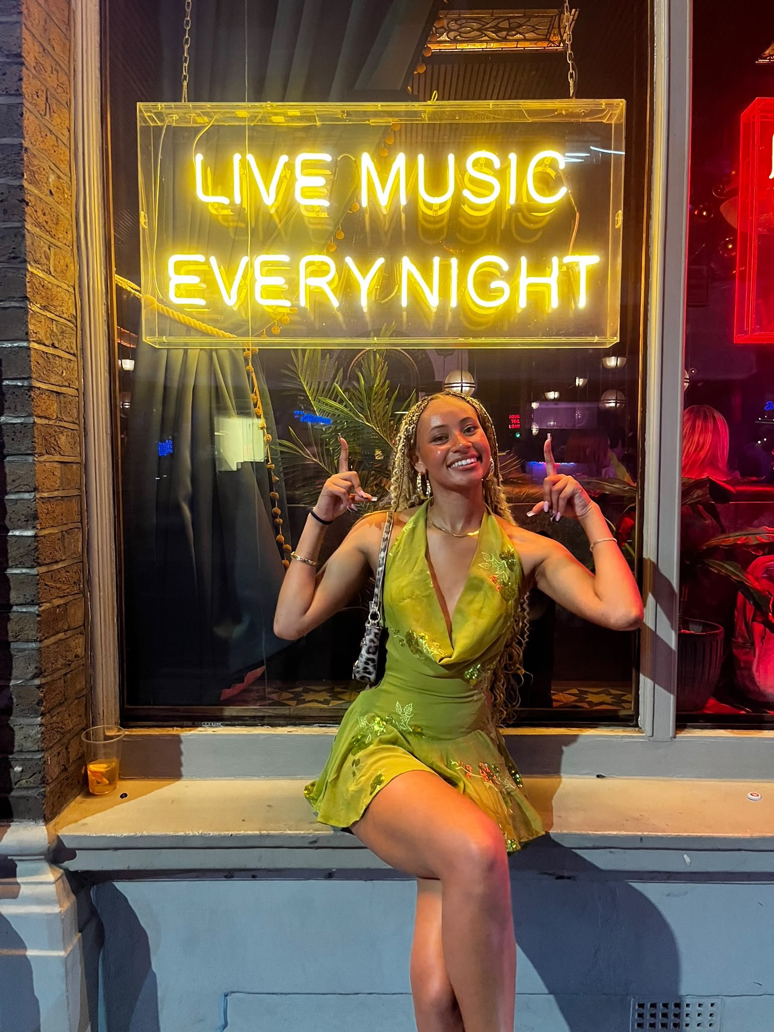 Lytoya Ri beneath a Live Music Every Night sign